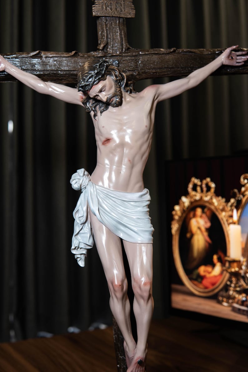 May include: A detailed sculpture of Jesus on the cross. The figure is depicted with a crown of thorns, a white loincloth, and visible wounds. The cross is made of dark wood, and the sculpture has a glossy finish.
