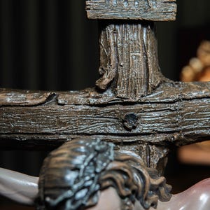May include: A detailed close-up of a crucifix statue. The wooden cross features the inscription "INRI" on a small sign. The statue depicts a figure with a crown of thorns, with a detailed face and beard. The cross is a dark brown color.