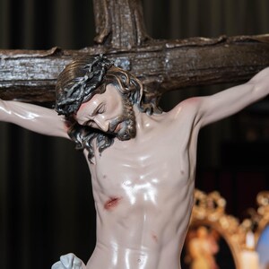 May include: A detailed statue of Jesus Christ on the cross. The sculpture features a crown of thorns, a beard, and a draped cloth around the waist. The cross is made of wood, and the figure has a realistic, pale complexion.