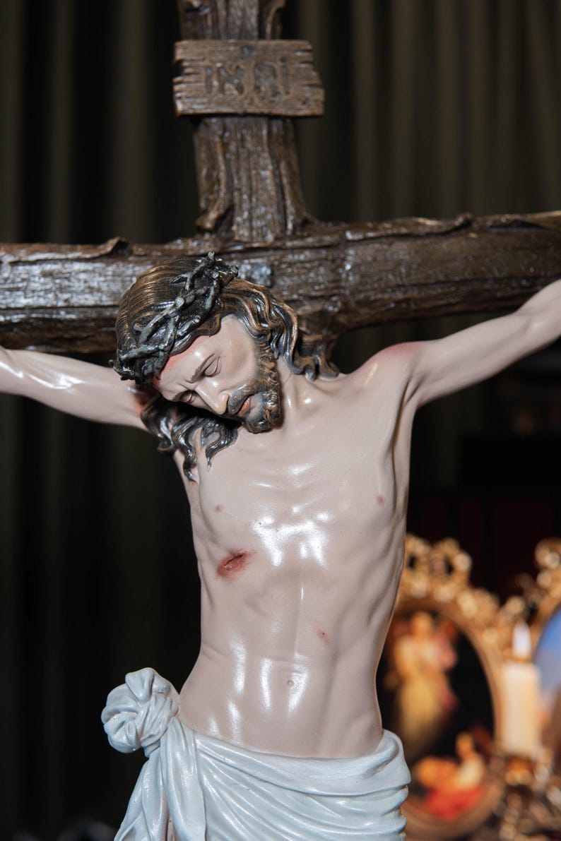May include: A detailed statue of Jesus Christ on the cross. The sculpture features a crown of thorns, a beard, and a draped cloth around the waist. The cross is made of wood, and the figure has a realistic, pale complexion.