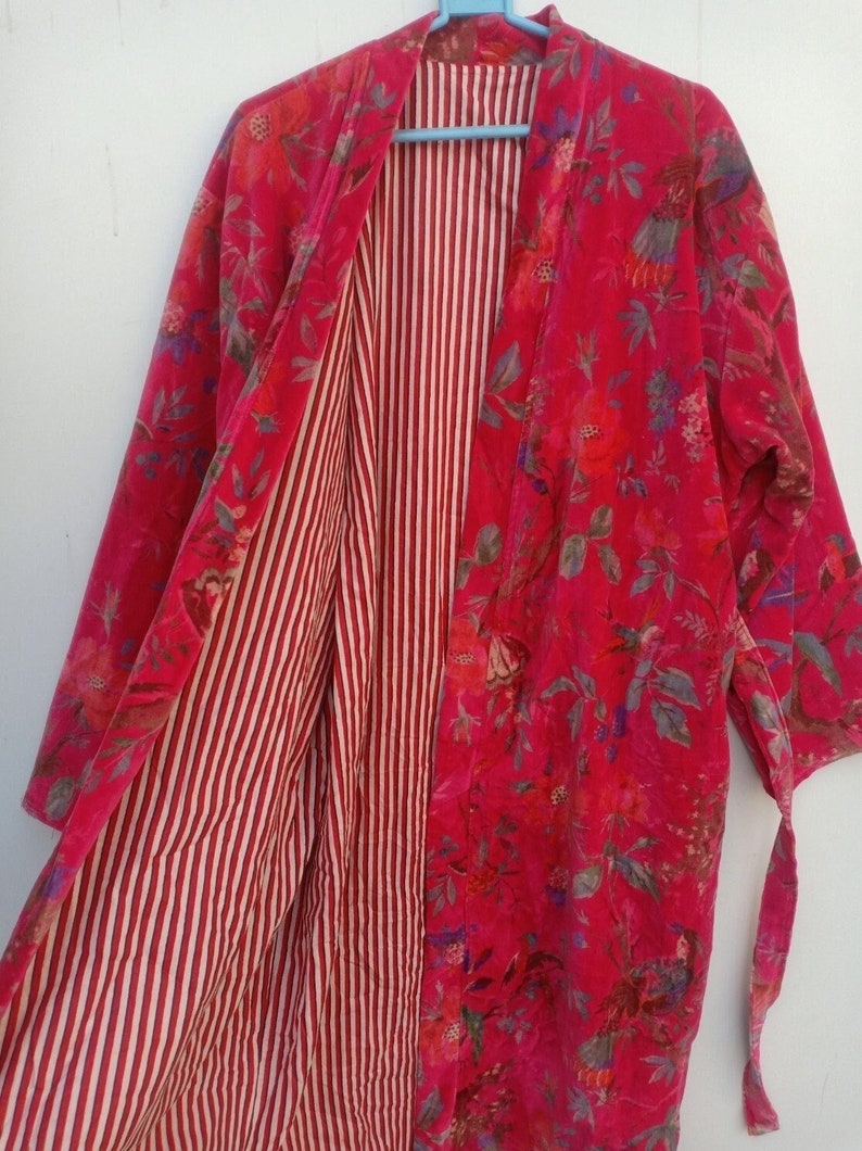 May include: A vibrant red kimono-style robe with a floral pattern on the outside and a striped pattern on the inside. The robe is open, revealing the contrasting patterns. The floral design includes shades of pink, green, and blue.
