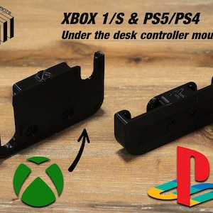May include: Two 3D printed black plastic mounts for video game controllers. The mount on the left is for an Xbox controller and the mount on the right is for a Playstation controller. The mounts are designed to be attached under a desk.