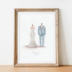 May include: Framed watercolor print featuring a wedding dress and a suit. The dress is white with a mermaid silhouette. The suit is light blue with a matching tie. The text "The [Last Name]" and a date are below the illustrations.
