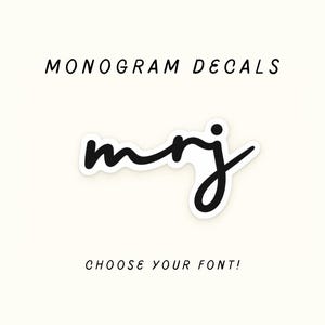 Può includere: Un adesivo monogramma nero con le lettere minuscole mrj in un carattere corsivo. Il testo MONOGRAM DECALS appare in lettere maiuscole nere sopra l'adesivo, e il testo CHOOSE YOUR FONT! appare in lettere maiuscole nere sotto l'adesivo.