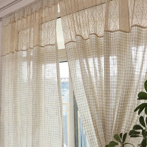 May include: White sheer curtains with a gingham pattern and a delicate lace trim. The curtains are hung on a white rod and are partially open, revealing a window with a view of a building.