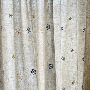 Puede incluir: Cortinas blancas y transparentes con diseños florales bordados en tonos azules y amarillos.