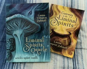May include: Two oracle card decks with a blue and white striped background. The deck on the left has a blue and green cover with a mushroom and the text "Liminal Spirits Oracle witch's spirit cards". The deck on the right has a yellow and orange cover with the text "Gateway to the Liminal Spirits" and the author's name "Laura Tempest Zakroff".