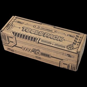 May include: A soldering kit with various tools, including blue wire cutters, a soldering iron, safety glasses, a screwdriver, and a small sponge. The tools are arranged on a white surface, with some items inside a cardboard box.
