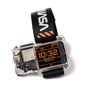 May include: A digital watch with a clear plastic casing revealing internal electronic components. The screen displays the time 10:32 and the date 24TH DEC 2024 in orange text. It features a black fabric strap with the white text NASA and orange stripes.