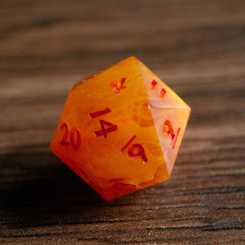 May include: A twenty-sided die with a marbled orange and yellow design. The numbers are etched in red. The die is designed for role-playing games.