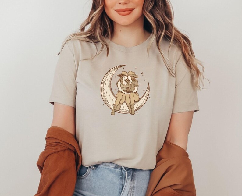 Two Sapphic Lesbian Cowgirls Sitting On Crescent Moon Tan Short Sleeve T-Shirt