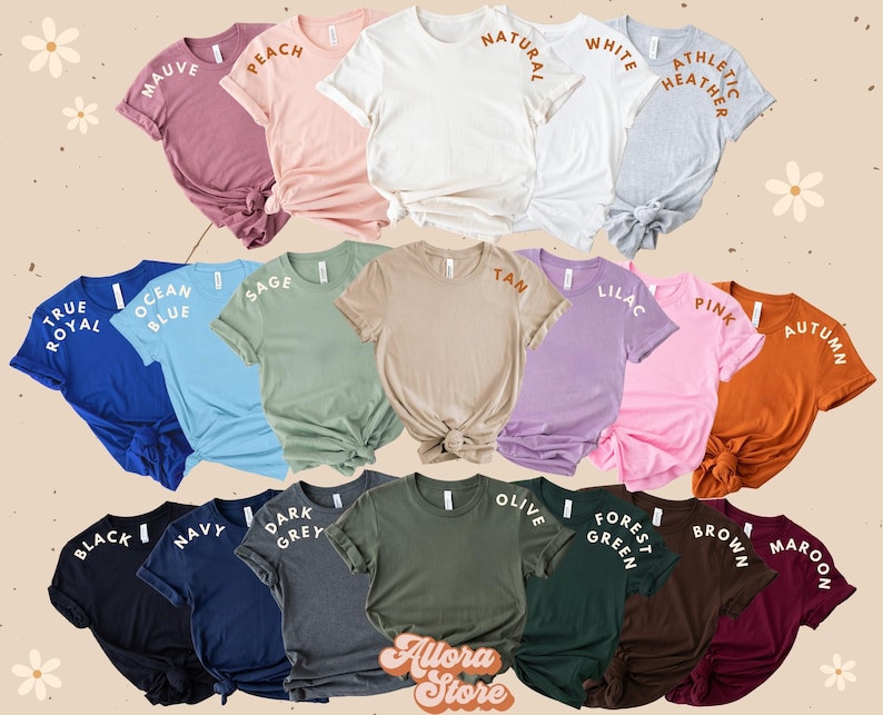 K&ouml;nnte beinhalten: Eine Auswahl an T-Shirts in verschiedenen Farben und Stilen, mit Textlabels, die die Farbnamen angeben. Die Farben umfassen Mauve, Pfirsich, Natur, Wei&szlig;, Athletik-Heather, True Royal, Ozeanblau, Salbei, Braun, Lila, Rosa, Herbst, Schwarz, Marine, Dunkelgrau, Oliv, Waldgr&uuml;n, Braun und Maroon.
