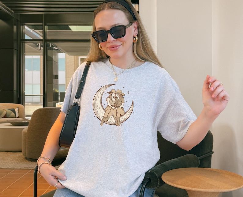Two Sapphic Lesbian Cowgirls Sitting On Crescent Moon Ash Short Sleeve T-Shirt