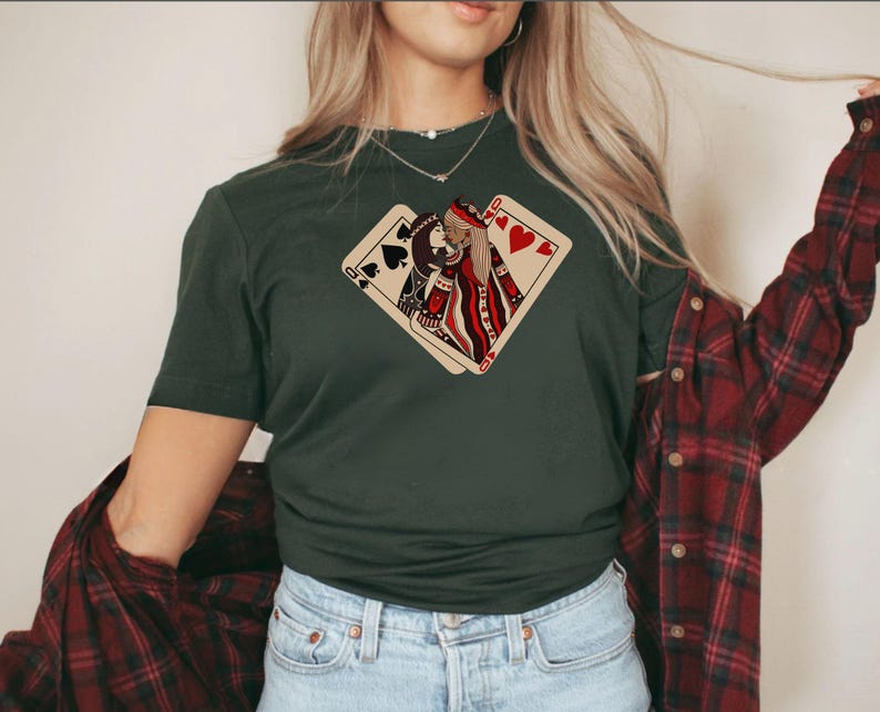 K&ouml;nnte beinhalten: Ein dunkelgr&uuml;nes T-Shirt mit einem Aufdruck von zwei Spielkarten, einer Herzdame und einem Pik-Buben, die sich &uuml;berlappen. Die Dame h&auml;lt eine rote Rose.