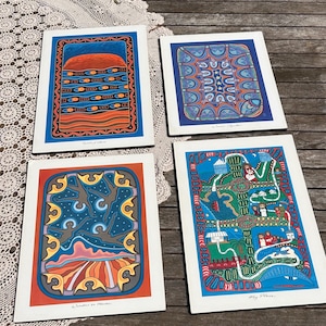 May include: Four rectangular art prints featuring vibrant, colourful illustrations. The top left print shows a sunset over water, the top right displays geometric patterns, the bottom left depicts figures in a starry sky, and the bottom right shows a landscape.