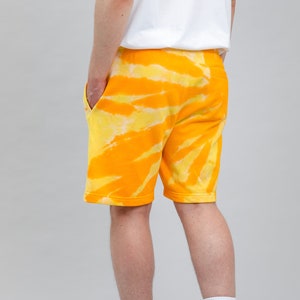 May include: Yellow and orange tie-dye shorts with a white waistband. The shorts are made of a soft, comfortable fabric and have a relaxed fit.