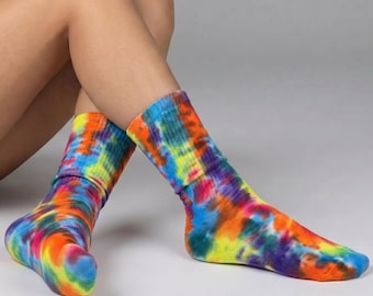 Peut inclure: Une paire de chaussettes tie-dye colorées. Les chaussettes présentent un mélange vibrant de couleurs, notamment orange, jaune, bleu et violet. Fabriquées dans une matière douce, elles sont conçues pour un usage quotidien confortable.