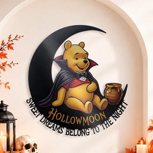 May include: A circular wall sign featuring a yellow bear dressed in a vampire cape and bowtie, sitting on a black crescent moon. The text reads HOLLOWMOON and SWEET DREAMS BELONG TO THE NIGHT. A small honey pot sits beside the bear on the moon.