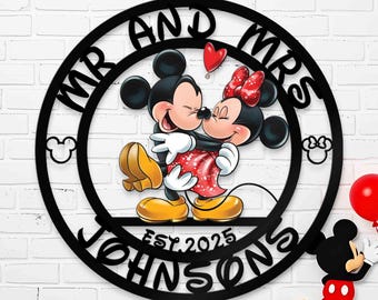 May include: Black metal circle with the text "Mr. and Mrs. Johnson Est. 2025" around the edge. Inside the circle is a cartoon image of Mickey Mouse and Minnie Mouse hugging.