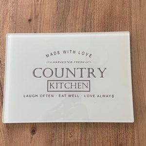 May include: White glass chopping board with the text "Made with Love - Harvested Fresh - Country Kitchen - Laugh Often - Eat Well - Love Always".