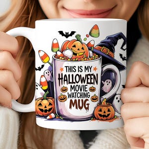 May include: White ceramic Halloween mug with a festive design. The mug features a pumpkin, witch hat, candy corn, and the text "THIS IS MY HALLOWEEN MOVIE WATCHING MUG". Perfect for enjoying your favorite Halloween beverages.