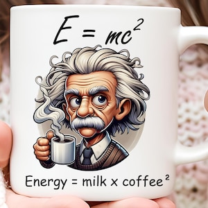 May include: White ceramic mug with a cartoon illustration of Albert Einstein holding a cup of coffee. The mug features the text "E = mc²" and "Energy = milk x coffee²".