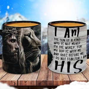 May include: Two black coffee mugs with a white background. One mug features a black and white image of Jesus and a lion. The other mug has the text "I AM THE SON OF A KING WHO IS NOT MOVED BY THE WORLD. FOR MY GOD IS WITH ME AND GOES BEFORE ME. I DO NOT FEAR FOR I AM HIS".