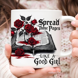 Pode incluir: Caneca de cerâmica branca com uma ilustração em preto e branco de um livro com rosas vermelhas e sangue pingando. O texto na caneca diz "Spread those pages like a good girl."