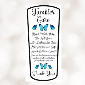 May include: A white sticker with black text and blue butterfly graphics. The text reads "Tumbler Care" and includes instructions for hand washing only, avoiding soaking, dishwashers, and microwaves. It also advises to avoid extreme heat and to handle with care. The sticker ends with "Thank You!"