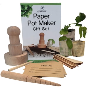 May include: A wooden paper pot maker kit with a wooden press, a wooden dibbler, and a stack of brown paper squares. The kit also includes a set of wooden plant markers and a small bag of seeds. The kit is packaged in a box with the words "Paper Pot Maker Gift Set" printed on it.