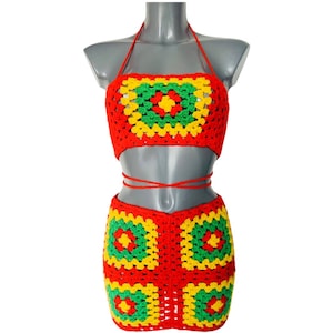 May include: A red, yellow, and green crochet two-piece outfit. The top is a halter-style crop top, and the bottom is a mini skirt. The outfit is displayed on a mannequin against a white background.