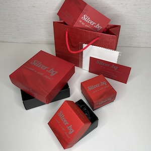 May include: Red gift boxes with the text "Silver.bg - and it will shine!" on them. The boxes are stacked on top of each other. There is a red shopping bag with a white cloth inside.