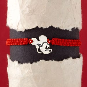 May include: Red string bracelet with a silver Mickey Mouse charm.