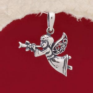 Puede incluir: Encanto de colgante de ángel de plata con alas detalladas y una trompeta. El ángel está tocando la trompeta y tiene un delicado diseño floral en el instrumento.