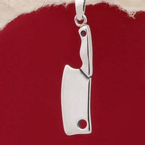 Op de afbeelding: Een zilveren hakmes-hanger met een lus aan de bovenkant om op te hangen. De hanger is een gedetailleerde replica van een hakmes.