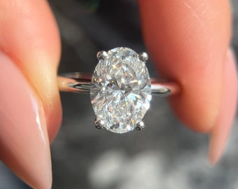 Può includere: Primo piano di un anello d'argento con un grande diamante ovale trasparente.