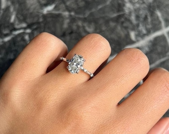 May include: A silver ring with an oval-shaped diamond set in a pave setting.