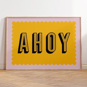 May include: A pink framed print with a yellow scalloped border and the word "AHOY" in black outlined letters.