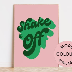 May include: A pink poster with green text that reads "Shake it off" in a retro font style. The poster has a white border and is framed.