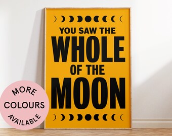 May include: A yellow poster with black text that reads "You saw the whole of the moon" with a crescent moon graphic on each side. The poster is framed in a light wood frame.