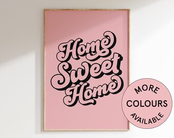 May include: A pink framed poster with the text "Home Sweet Home" in a retro, black, stylized font. The poster has a white background and a wooden frame. A white circle with black text says "More Colors Available".