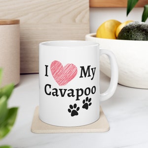 May include: White ceramic mug with a pink heart and the text "I love my Cavapoo" in black. Two black paw prints are below the text.