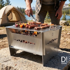 Op de afbeelding: Een draagbare houtskoolgrill van roestvrij staal met een rechthoekige vorm, voorzien van een lasergesneden driehoekspatroon aan de zijkanten, een metalen grillrooster en handgrepen. De tekst D! Maker en Digital files ONLY is zichtbaar.