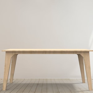 Op de afbeelding: Een lichte houten tafel met een rechthoekig blad en vier schuin geplaatste poten. De tafel staat in een kamer met witte muren en een houten vloer.