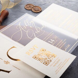 Close-up of a clear acrylic wedding invitation with rose gold foil, white sleeve envelope and optional QR RSVP and details cards.