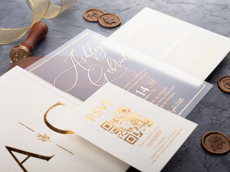 Close-up of a clear acrylic wedding invitation with rose gold foil, white sleeve envelope and optional QR RSVP and details cards.