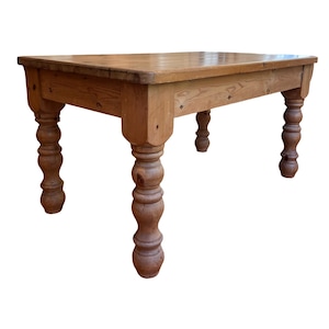 May include: A rectangular wooden table with a natural light brown finish and visible wood grain. The table features a flat top surface and four thick, turned legs with a rounded, stacked bulbous design that provides sturdy support for the frame.