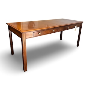 May include: A rectangular wooden desk with a glossy finish. The desk has three drawers with brass knobs and four slender legs. The desk is approximately 72 inches long, 36 inches wide, and 30 inches high.