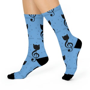 May include: A pair of blue socks with a black cat and treble clef pattern. The socks are made of a soft, comfortable material and are perfect for everyday wear.