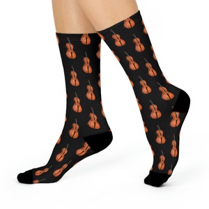 May include: A pair of black socks with a repeating pattern of brown cellos. The socks are shown on a model's legs.